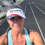 Coach Erin Byrge of 3 Goals Multisport Coaching smiling on a running track wearing a Team 3G visor.