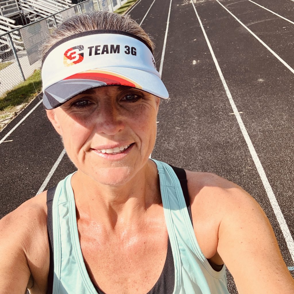 Erin Byrge triathlon coach wearing Team 3G visor on a track representing personalized coaching and training guidance