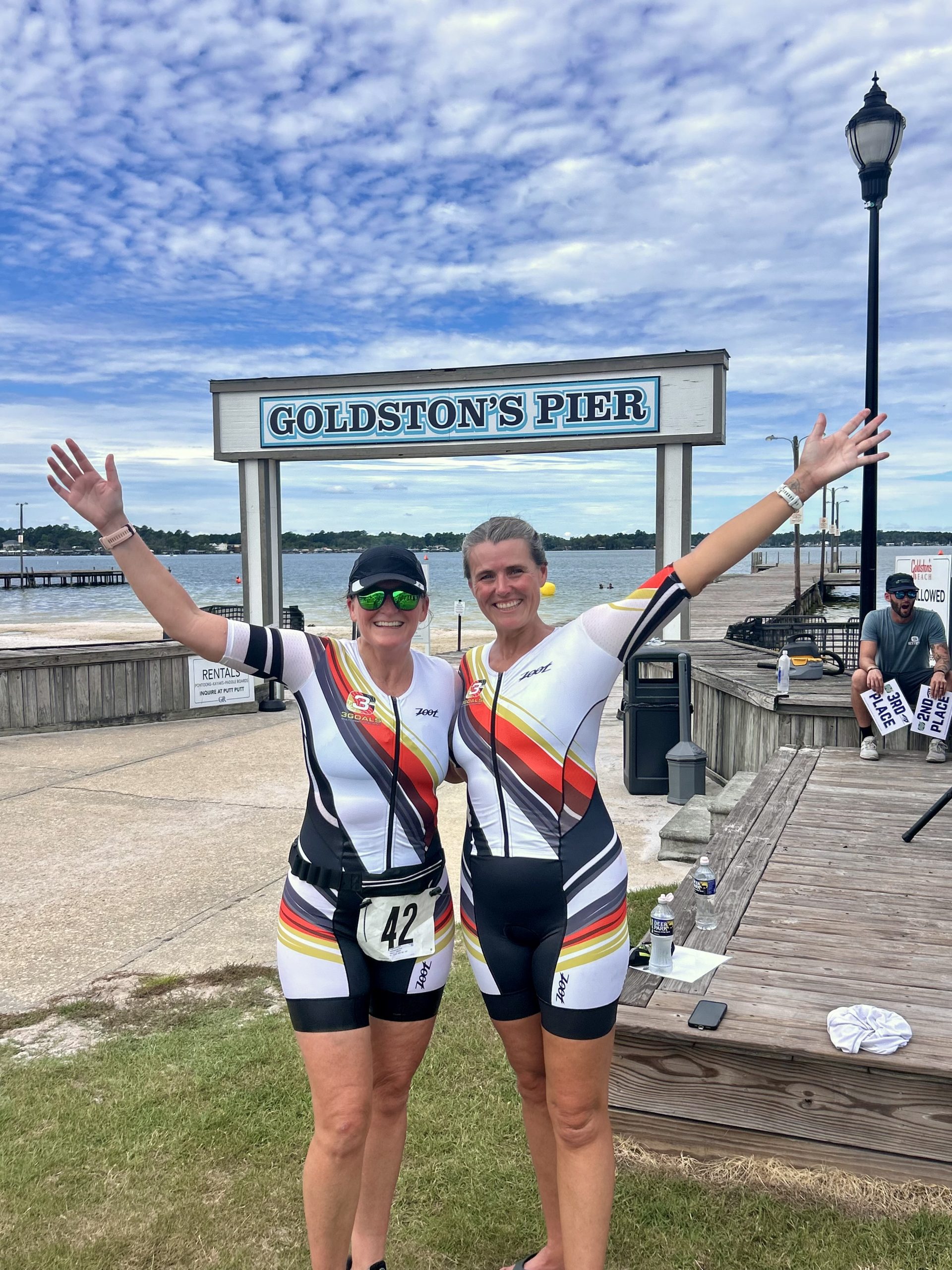 Two Team 3G athletes in matching kits celebrating at Goldston’s Pier — join Team 3G.