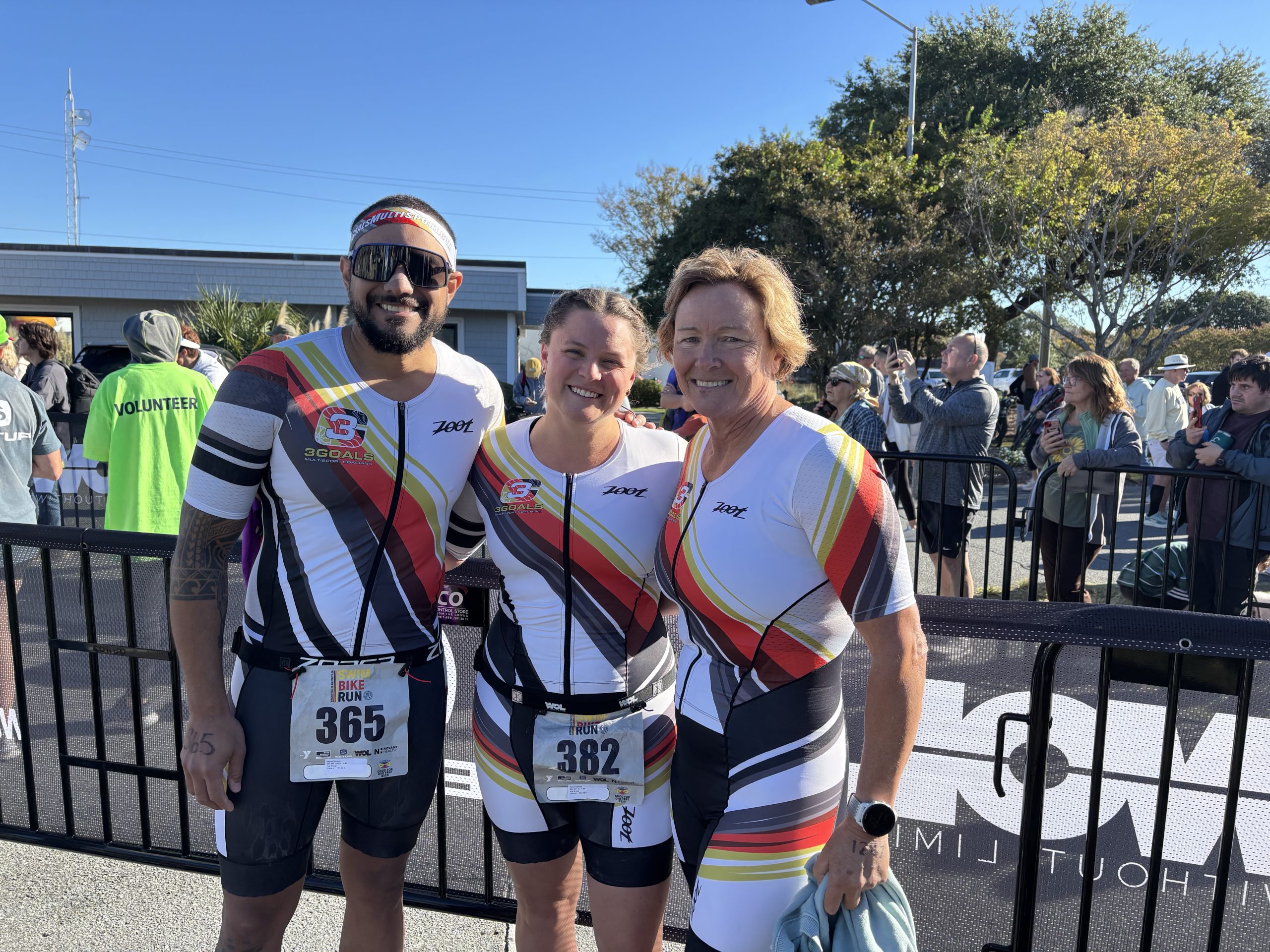 Three smiling Team 3G athletes in matching triathlon kits at a race venue — join Team 3G.